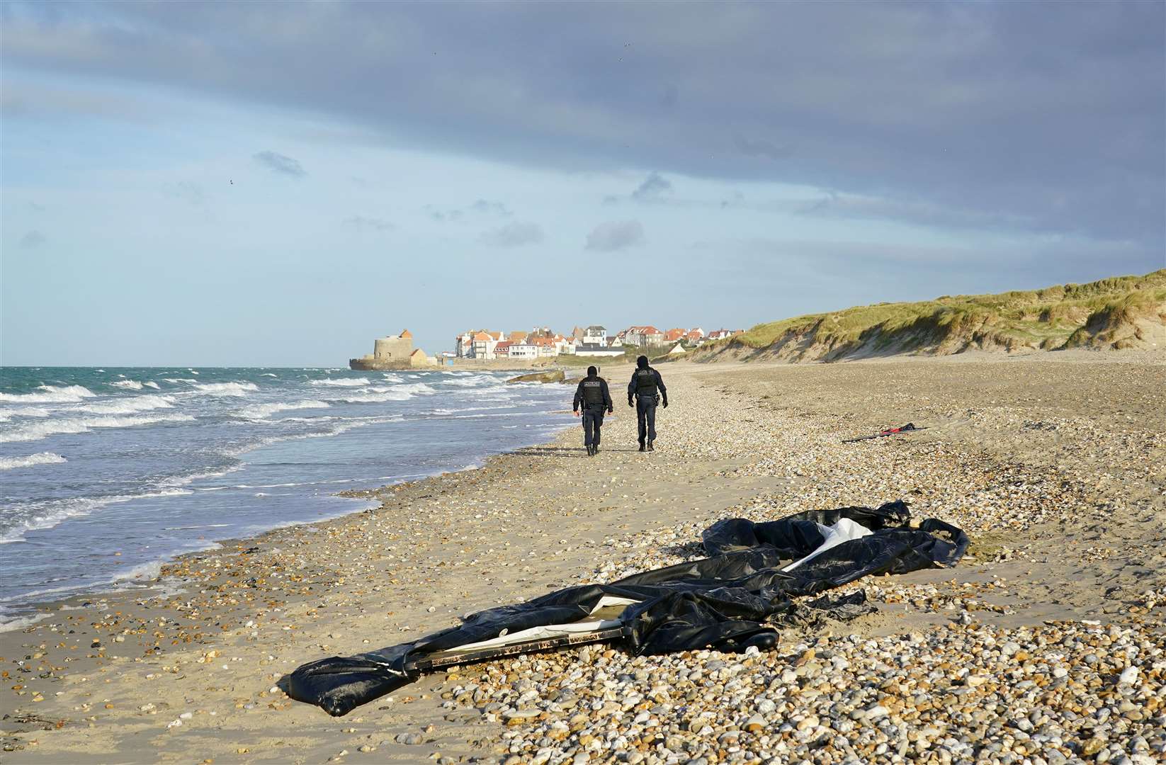 French police pass a deflated dinghy on the beach in Wimereux near Calais (Gareth Fuller/PA)