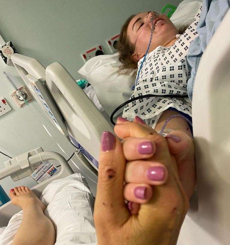 Mum Kirsten holding daughter Jess' hand in hospital