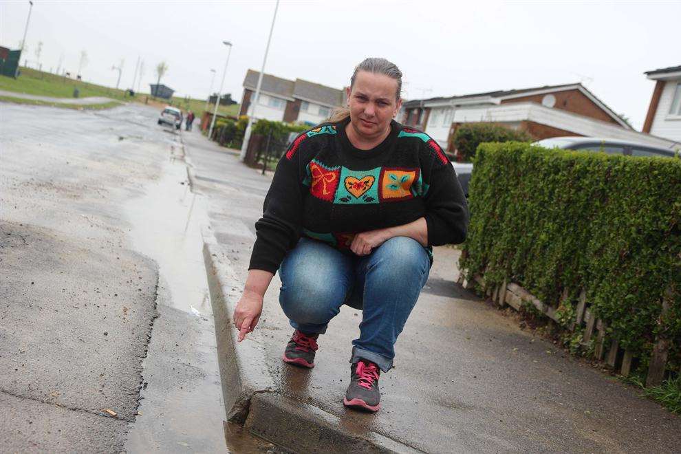 Joy Ewart next to the water leak outside her house