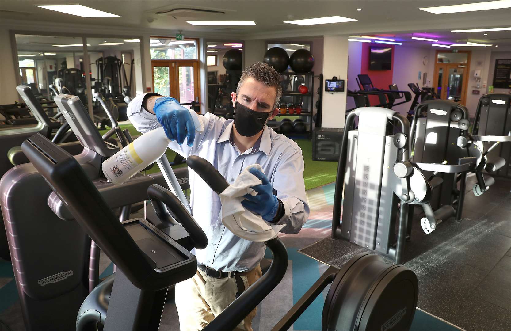 Staff clean a cross trainer ahead of reopening (Martin Rickett/PA)