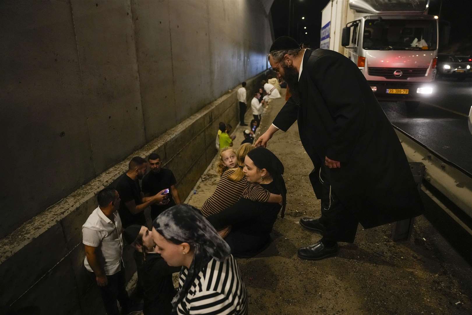 People take cover on the side of a road as a siren sounds a warning of incoming missiles fired from Iran in Shoresh, between Jerusalem and Tel Aviv in Israel on Tuesday (AP Photo/Ohad Zwigenberg)