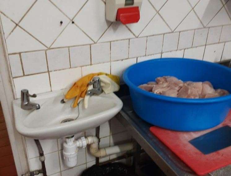 Yellow marigold gloves used for handling raw chicken in the adjacent sink were being stored in the wash hand basin to the rear of the kitchen behind the taps at Paper Duck World Buffet in Ashford. Picture: Ashford Borough Council