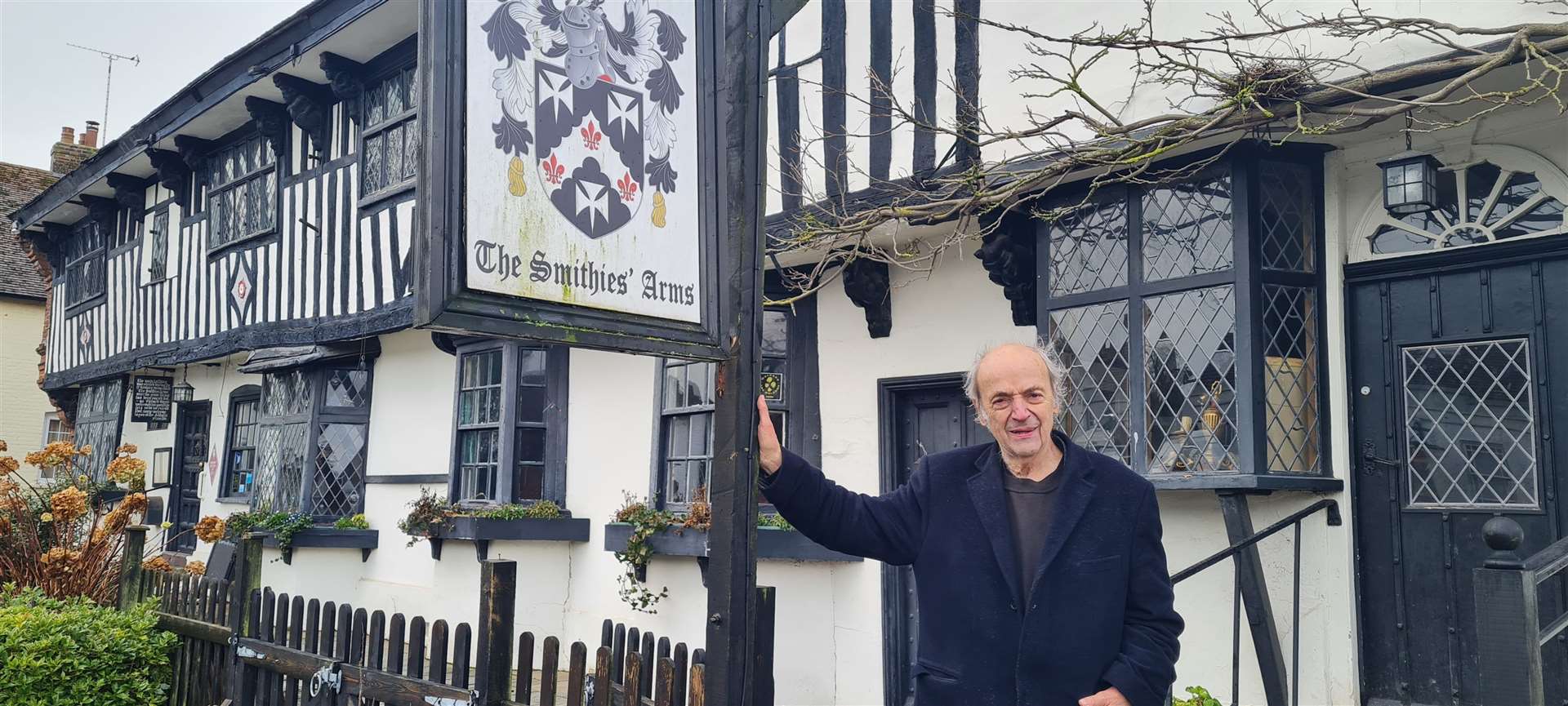 Peter Malkin outside the Abbot's Fireside at Elham where its original name of the Smithies Arms still hangs