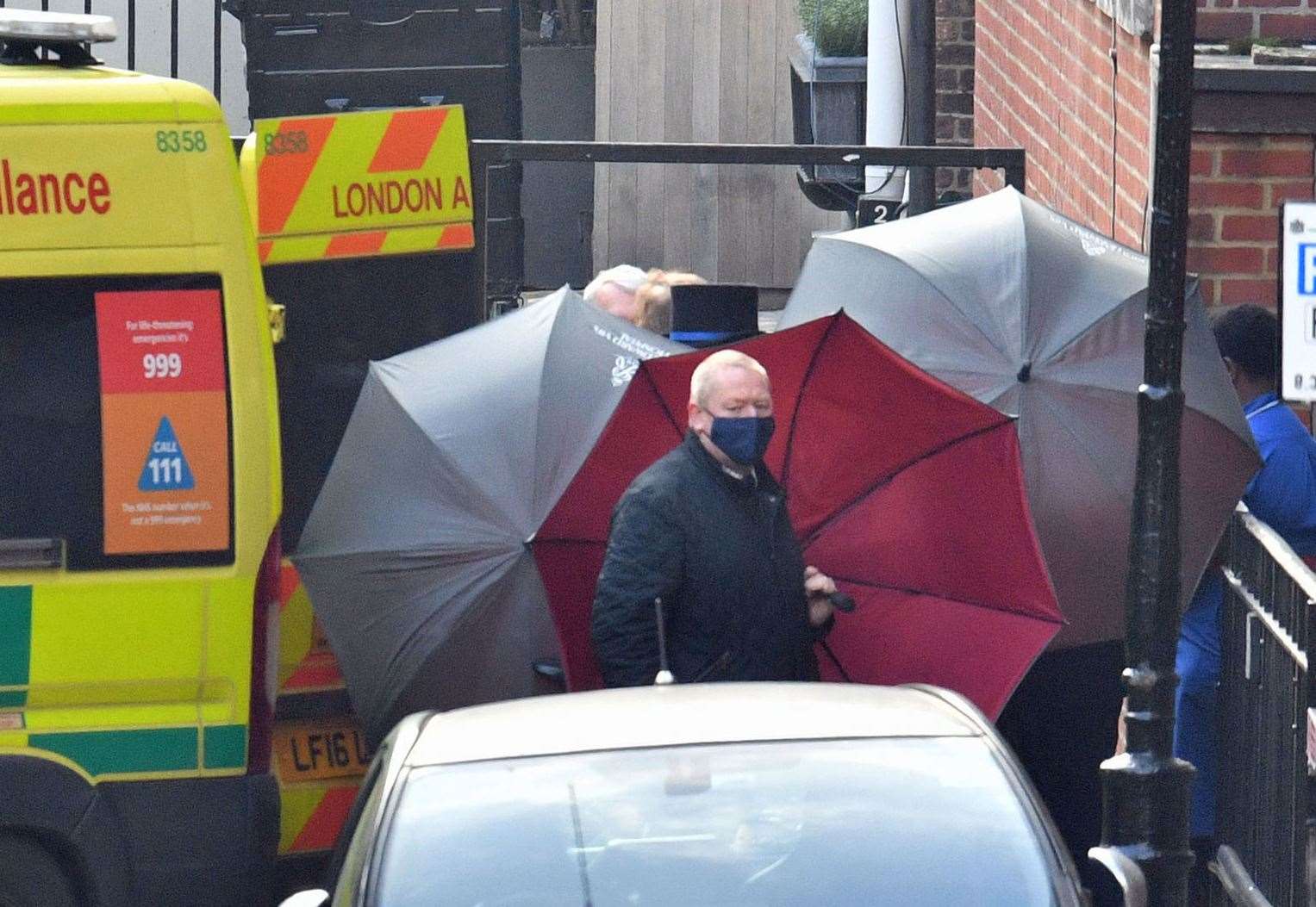 Staff shielded the hospital’s rear exit with umbrellas as Philip left (Dominic Lipinski/PA Wire)