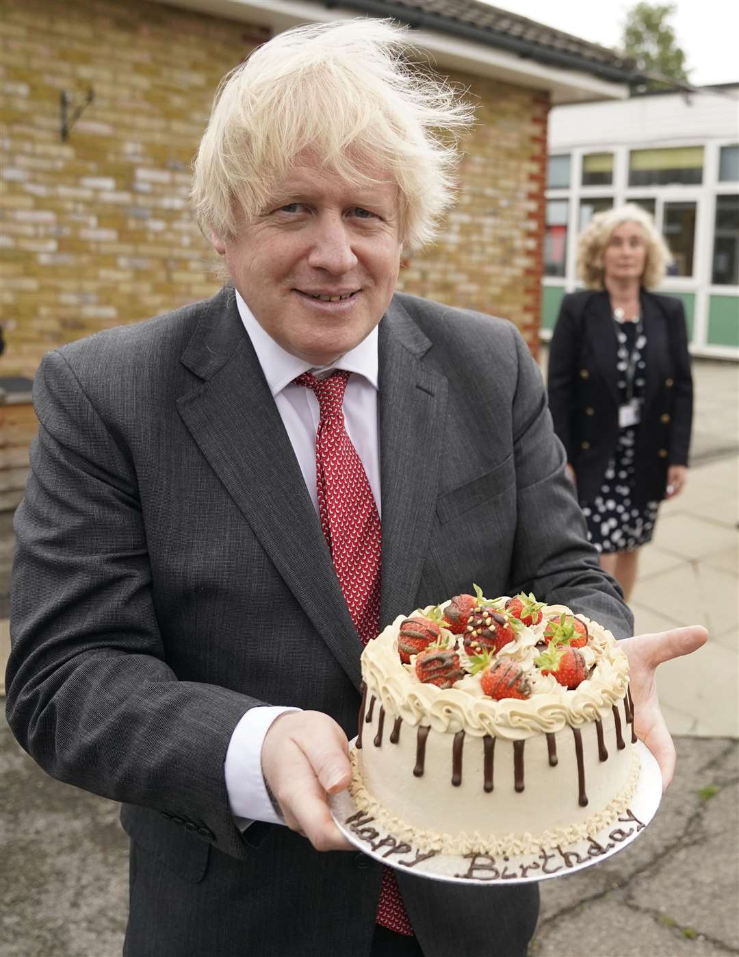 Boris Johnson holds up a birthday cake – baked for him by school staff – during a visit to Bovingdon Primary Academy (Andrew Parsons/No 10)