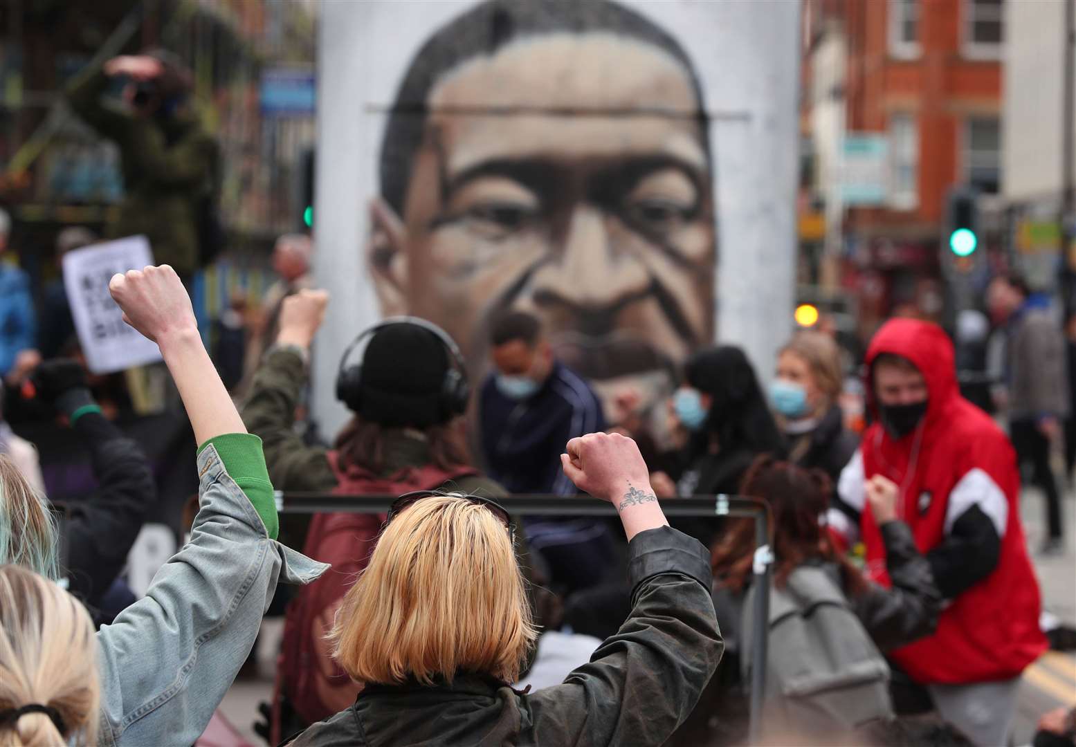 Protesters in Manchester take a knee in front of a mural of George Floyd (Peter Byrne/PA)