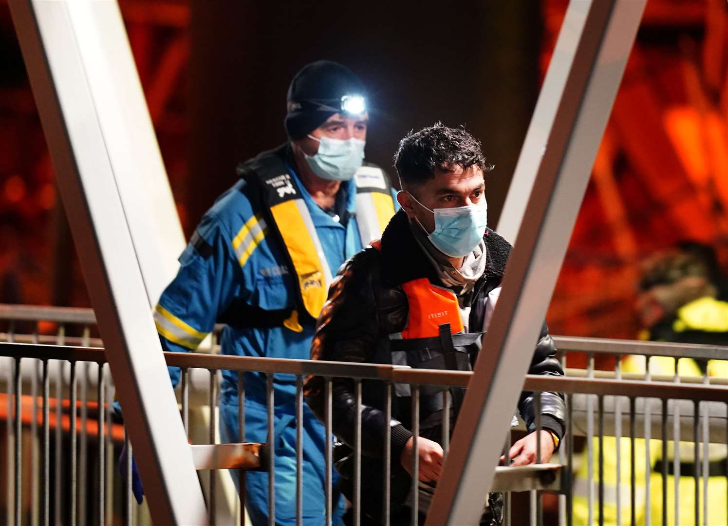 A man is escorted ashore by a Coastguard officer (Gareth Fuller/PA)