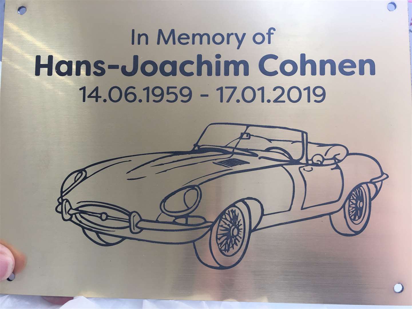 A plaque being placed at a memorial tree planted at the company's factory reflecting Mr Cohnen's love of classic cars