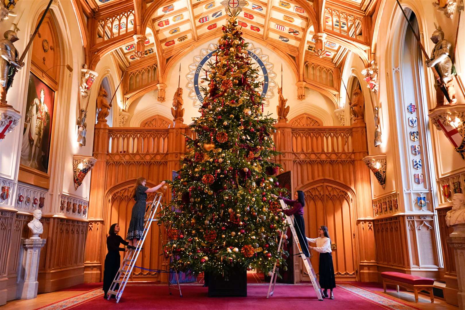 Royal Collection Trust staff used ladders to add the finishing touches to a tree in St George’s Hall, Windsor Castle (Andrew Matthews/PA)