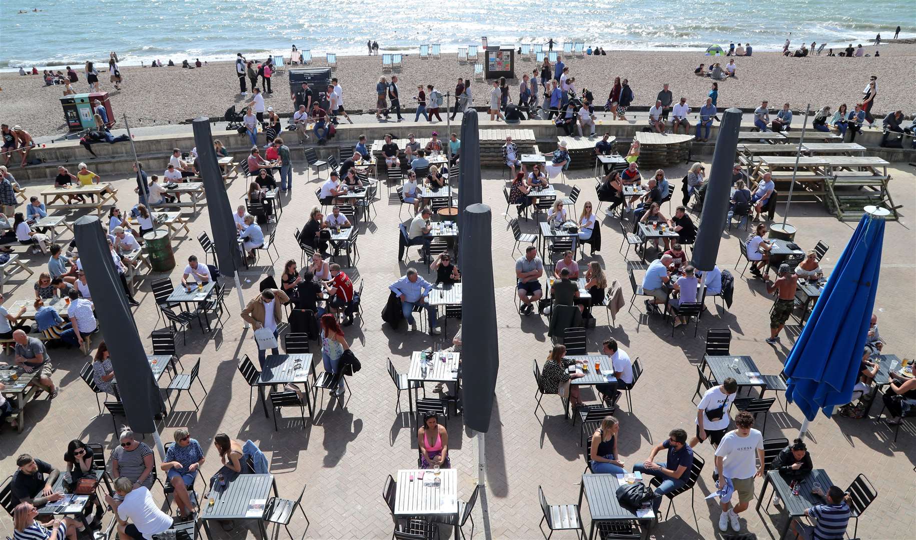 Customers enjoy the sunshine in a bar on the promenade in Brighton (Gareth Fuller/PA)