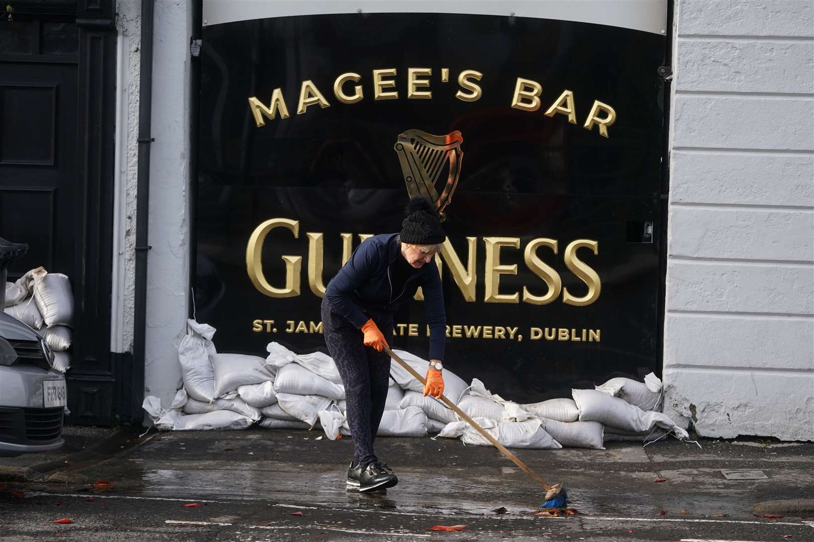 Delia Magee sweeps up outside Magee’s Bar, which has been in her husband’s family since 1913, as the clear up begins in Newry Town, Co Down (Brian Lawless/PA)