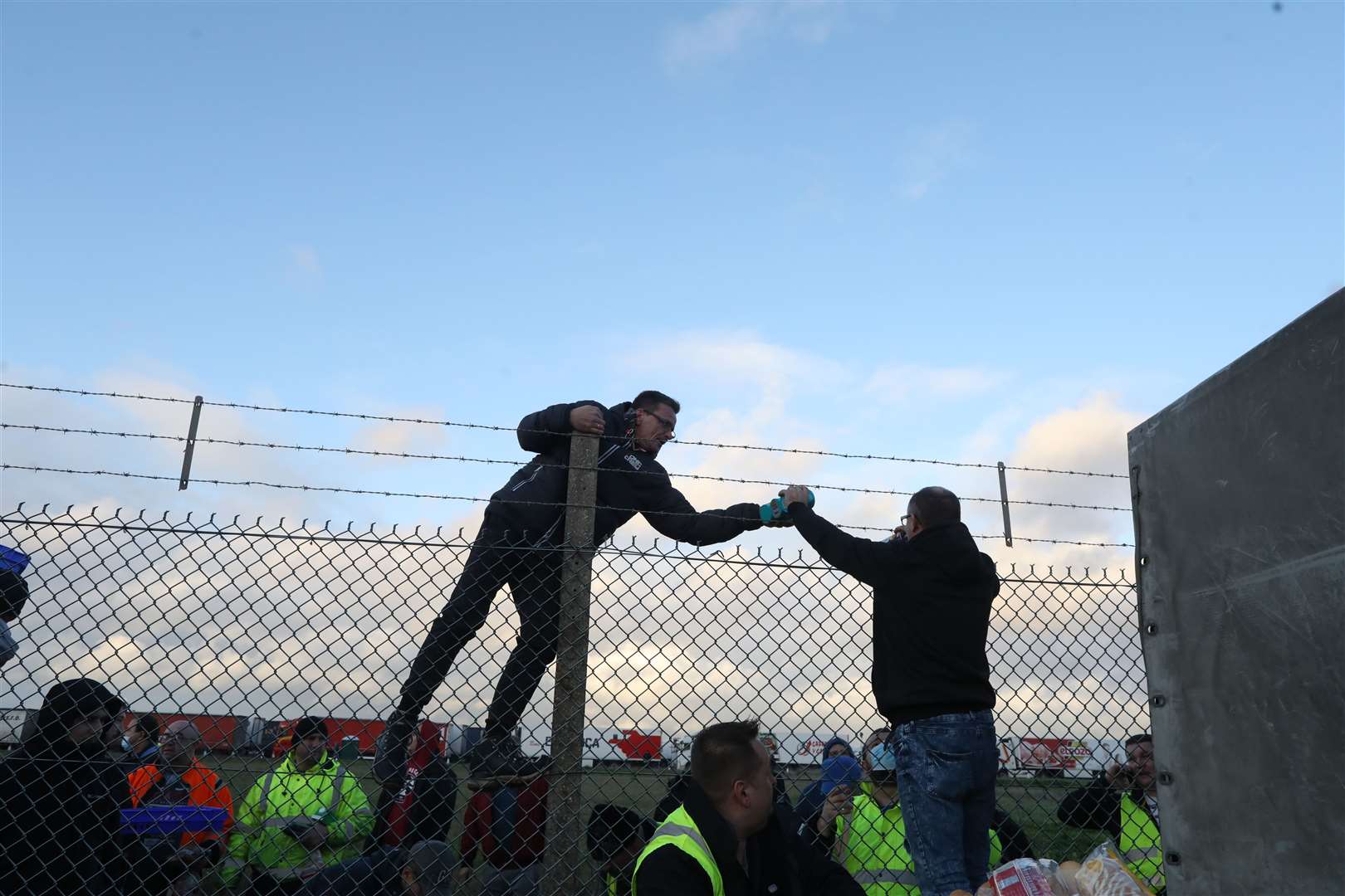 Cans of baked beans are handed over the fence. Picture: Barry Goodwin