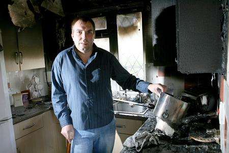 Jason Peterson with the chip pan in the remains of his wrecked kitchen