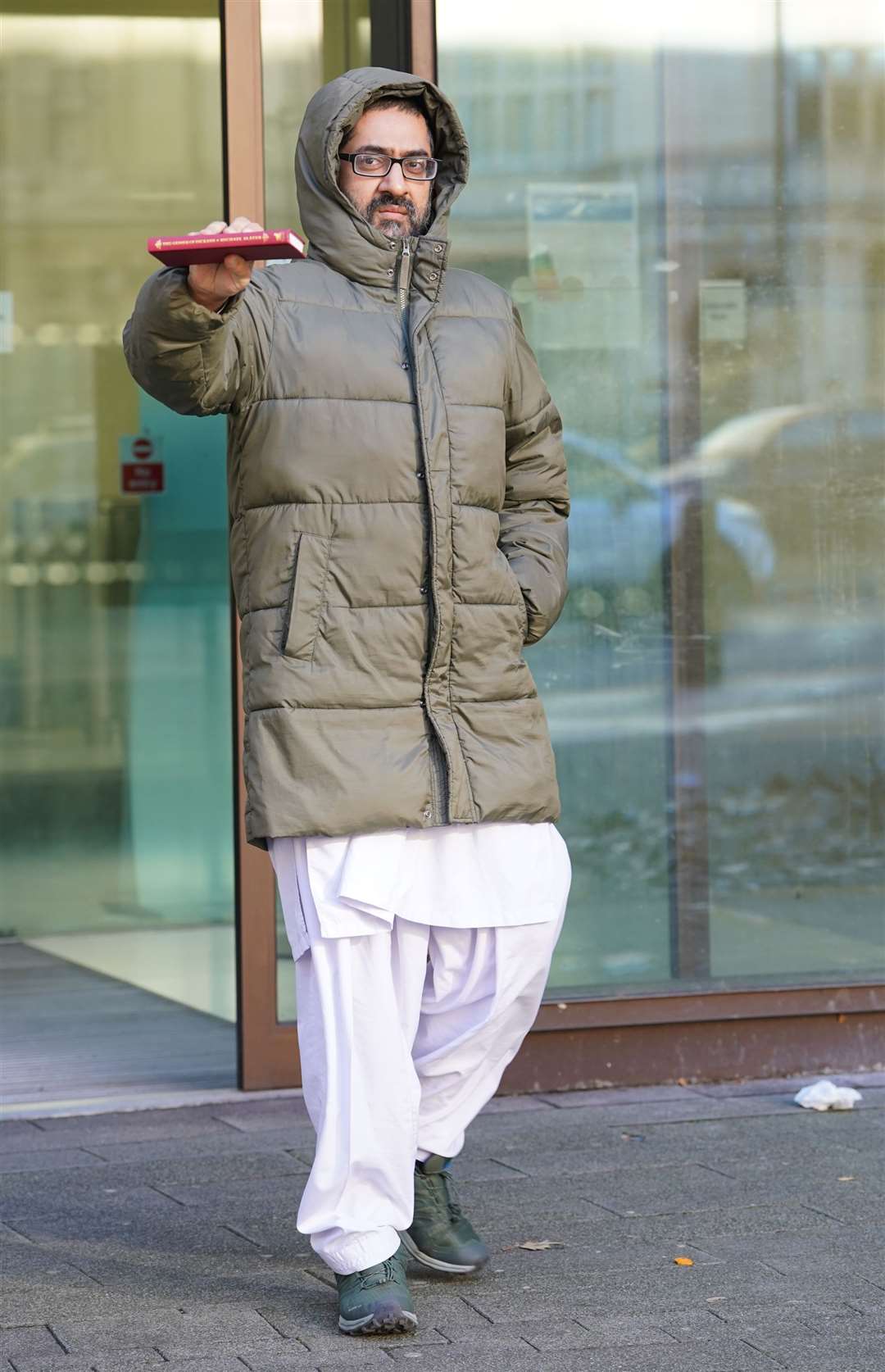 Urslaan Khan holds up a copy of The Genius Of Dickens by Professor Michael Slater as he leaves Westminster Magistrates’ Court in November (PA)