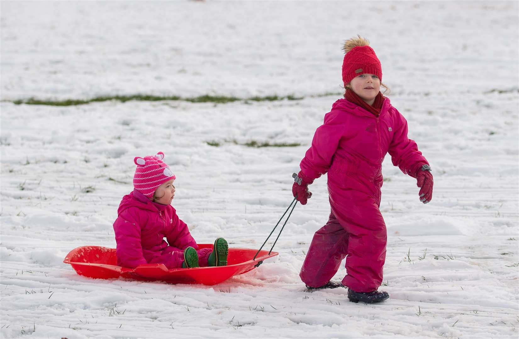 Farah, four, pulls her sister Niamh through the snow in a park in Newcastle-under-Lyme, Staffordshire (Joe Giddens/PA)