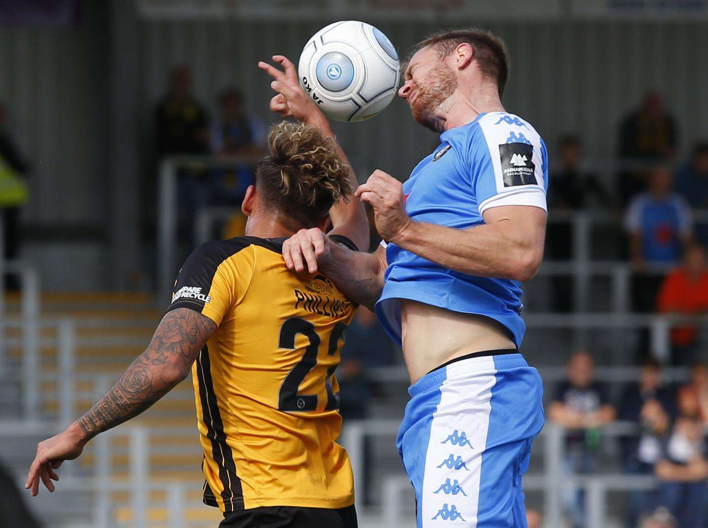 United midfielder Michael Phillips and Harrogate's Kevin Langmead leap into action Picture: Andy Jones