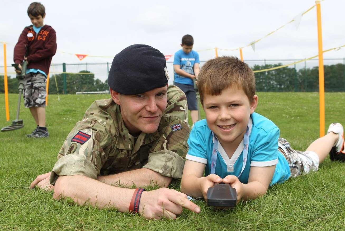 Sapper James Dobbs helps Lewis Machray-Bruce, seven, use a hand-held metal detector