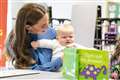 Kate cuddles baby as she learns about innovative education project