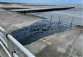 Contractor pours black surface water on seafront promenade