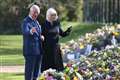 Charles and Camilla view flowers left in memory of Philip