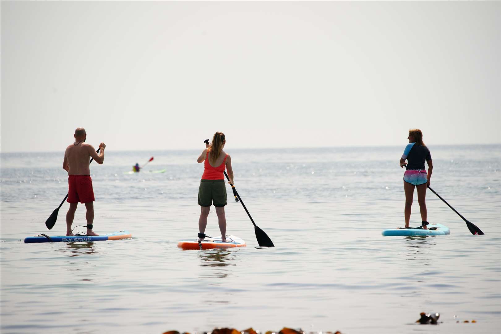 People on paddleboards in the sea in St Michael’s Bay in Cornwall (Ben Birchall/PA)