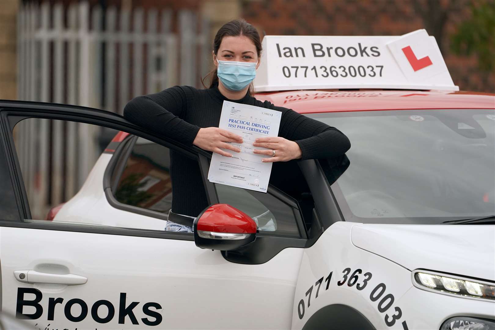 Jade Paxton, 30, a keyworker from Bedlington, Northumberland, holds up her pass certificate after successfully completing her driving test in Blyth (Owen Humphreys/PA)