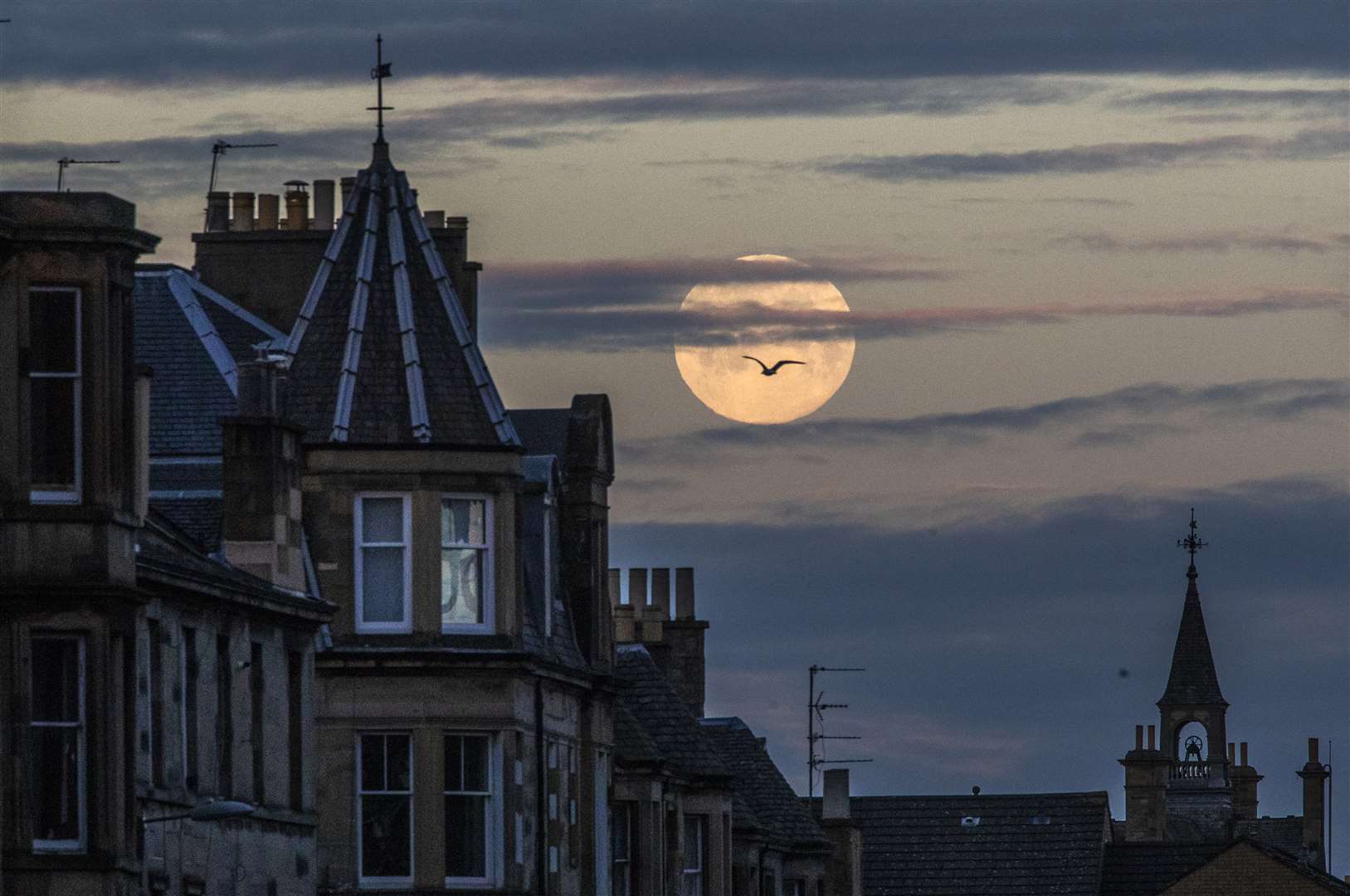 The pink supermoon is seen setting behind the rooftops in Edinburgh (Jane Barlow/PA)