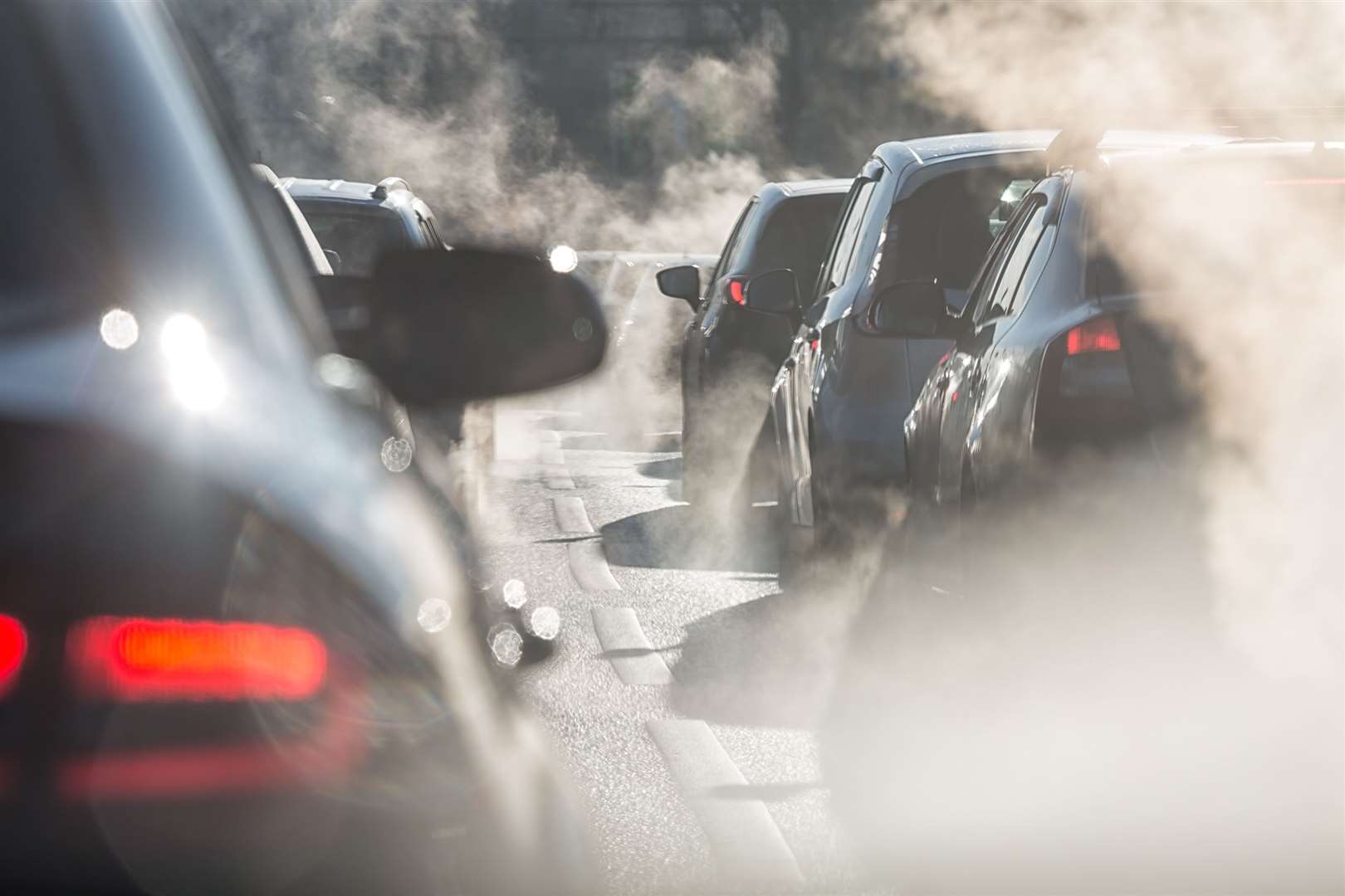 Blurred silhouettes of cars surrounded by steam from the exhaust pipes. Stock picture