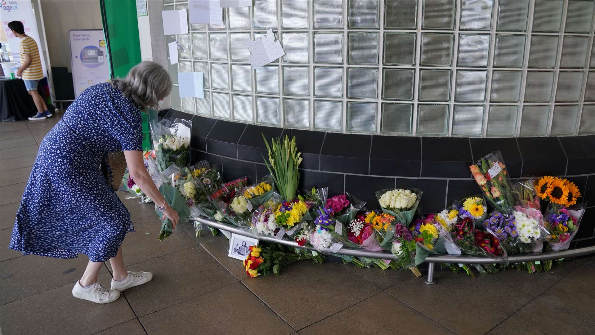 A woman leaves flowers outside Perivale Tesco, Greenford, where 87-year-old Thomas O’Halloran used to play his accordion (Jonathan Brady/PA)