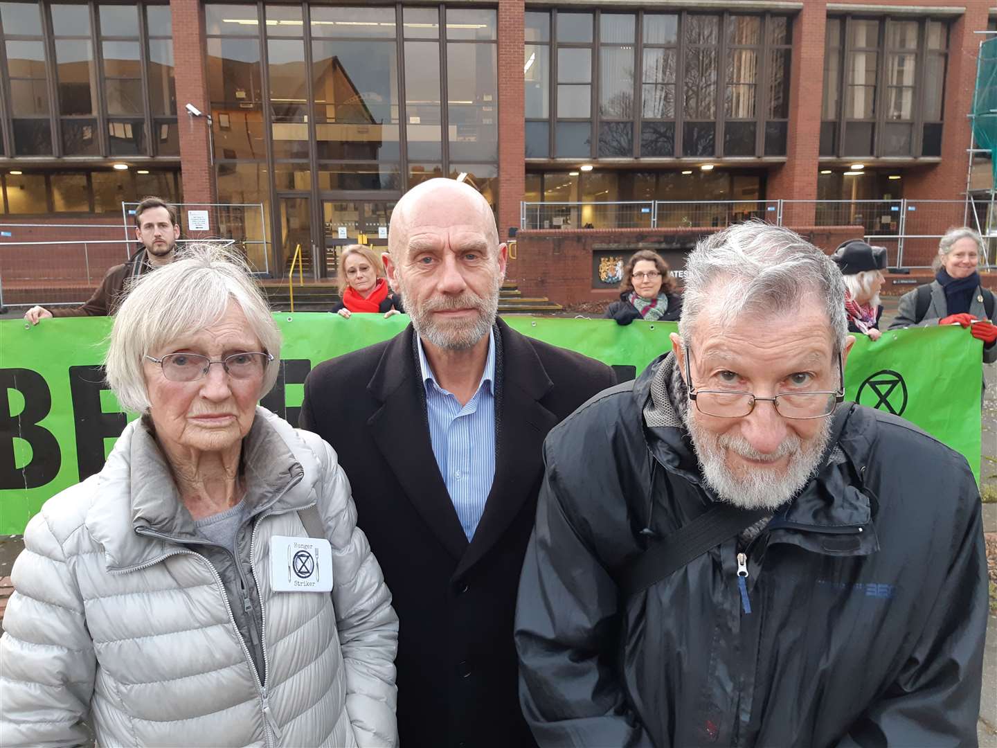 Pethick, Halladay and Lynes (right) outside court today after their hearing. Extinction Rebellion supporters are in the background