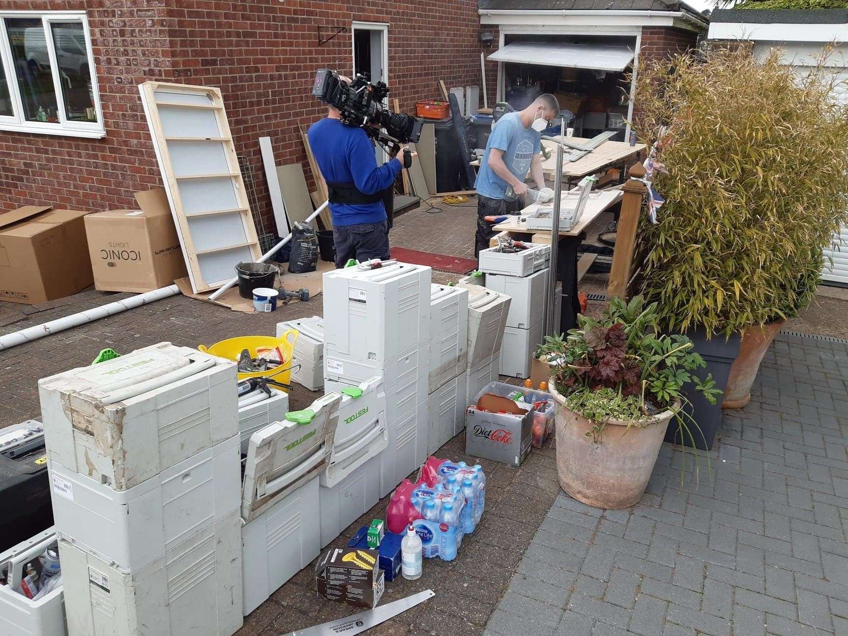 A cameraman films a carpenter cutting wood