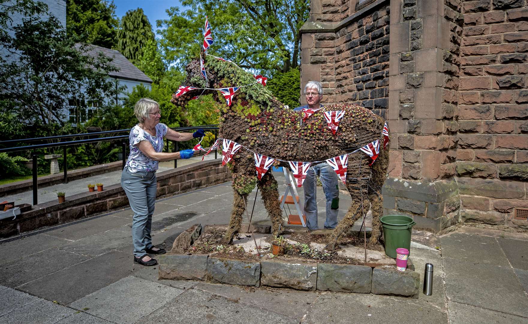 Wendy Doig and Roy Barker from St James Church in Woolton Village dress Jimmy the War Horse ahead of VE Day celebrations (Peter Byrne/PA)