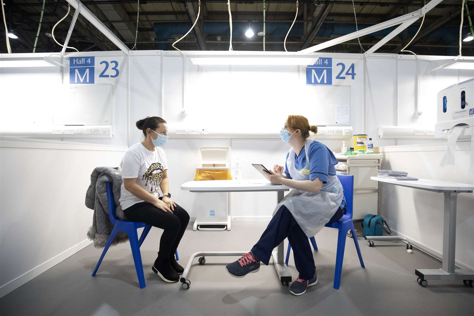 Nurse Eleanor Pinkerton speaks with one of the health and social care staff before administering a coronavirus vaccine at the NHS Louisa Jordan Hospital in Glasgow (PA)