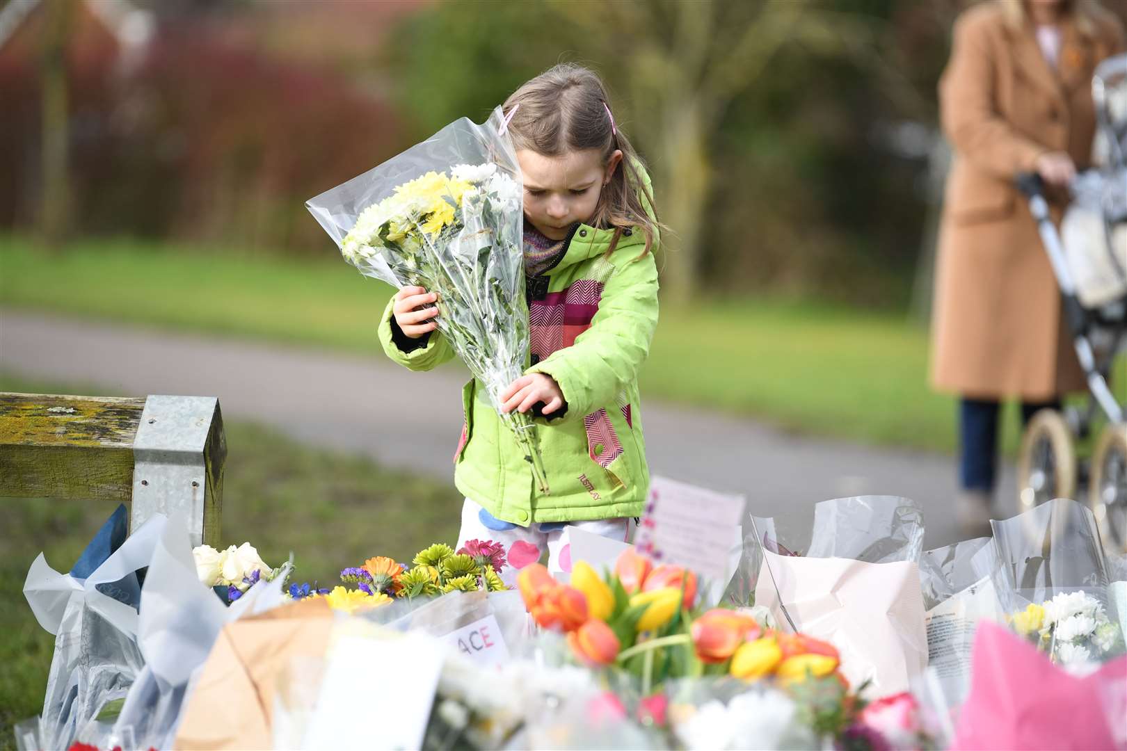 Noelle Simmons, four, leaves a floral tribute outside the home of Sir Tom in Marston Moretaine (Kirsty O’Connor/PA)