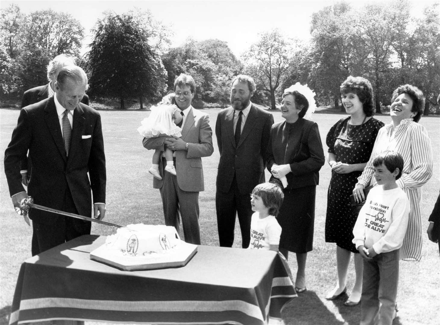 Patron of the British Heart Foundation the Duke of Edinburgh in the grounds of Buckingham Palace cutting a heart-shaped cake to give a royal send-off to Heart Week ’85 (PA)