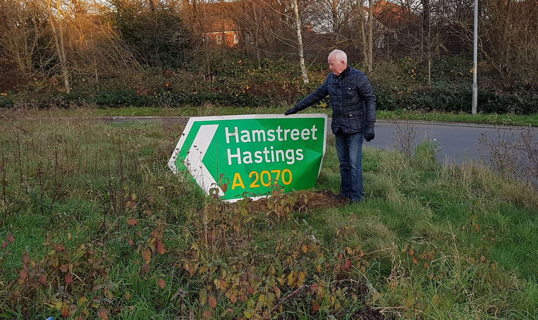 Mr Murray-Roscoe inspects a damaged sign on the roundabout