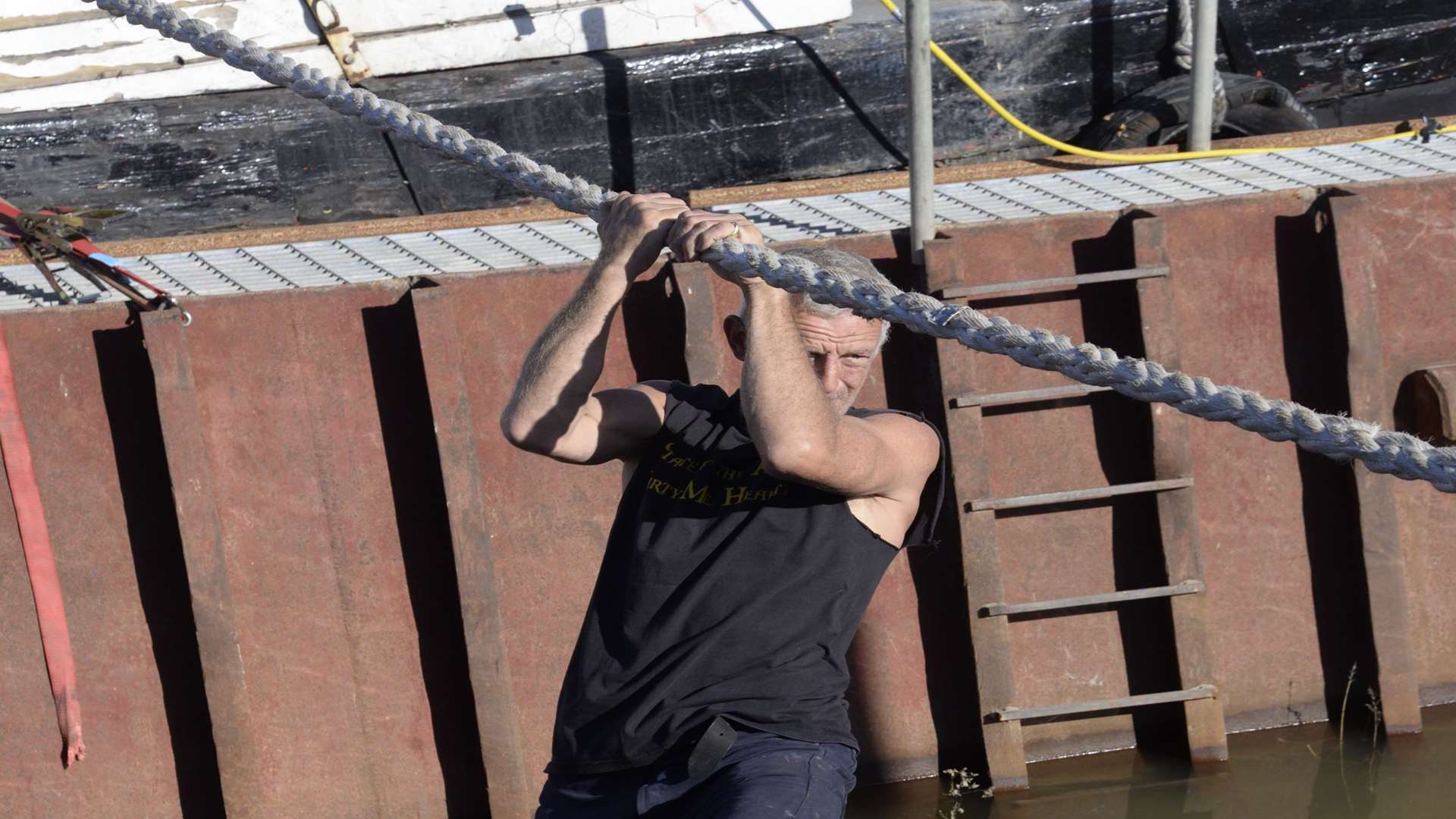 Finbarr O'Brien uses a rope mooring line to cross from his ship