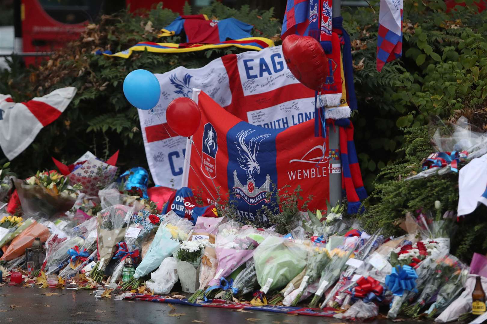 Floral tributes and Crystal Palace football colours left near the scene where a tram crashed, killing seven people, in Croydon, south London (Steve Parsons/PA)