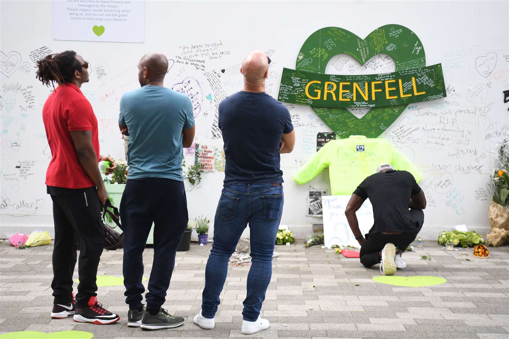 People at the Grenfell Memorial Community Mosaic at the base of the tower block (PA)