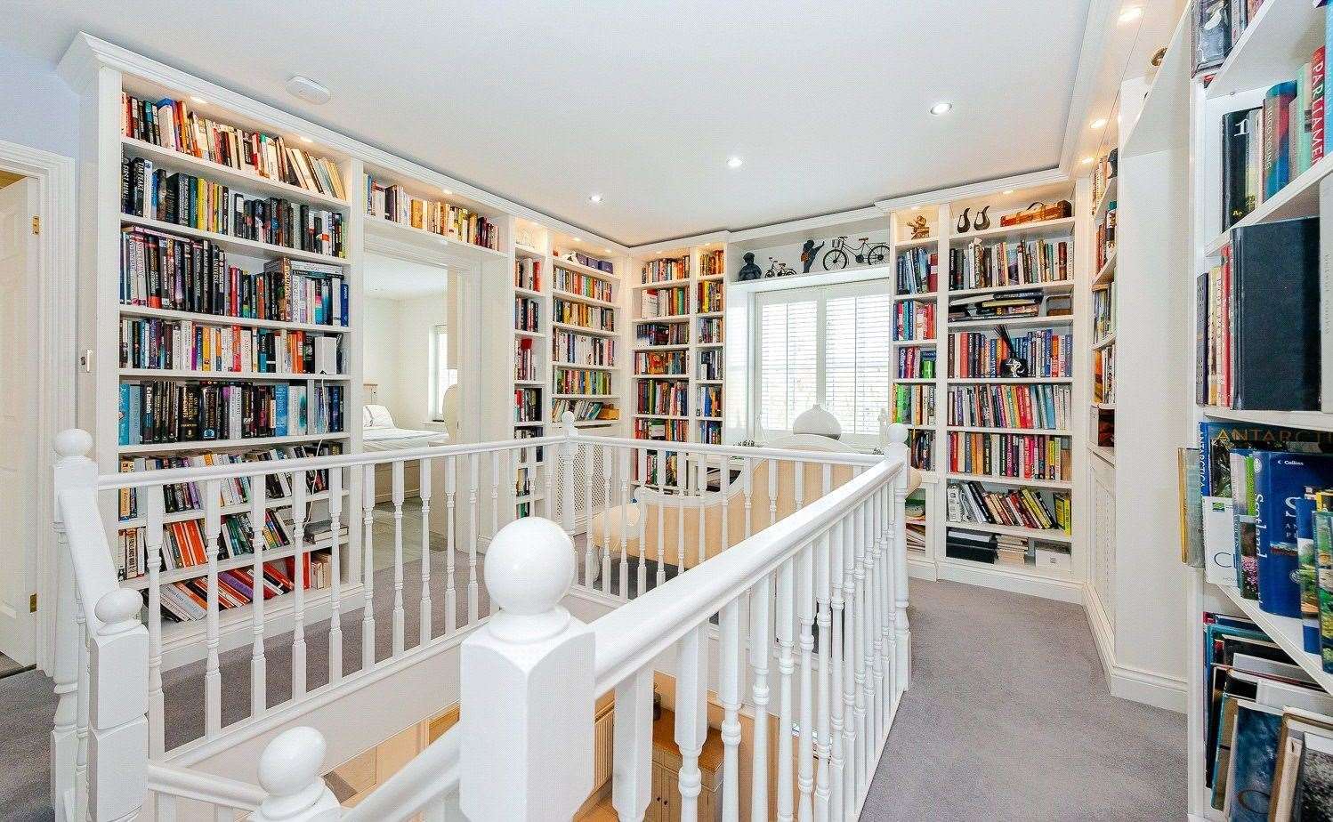 At the top of the stairs, the large landing is fitted with floor to ceiling bookshelves