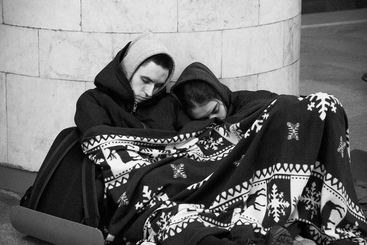 Civilians are seen huddled together under a blanket and wearing layers of clothing (Maria Volkova/PA)