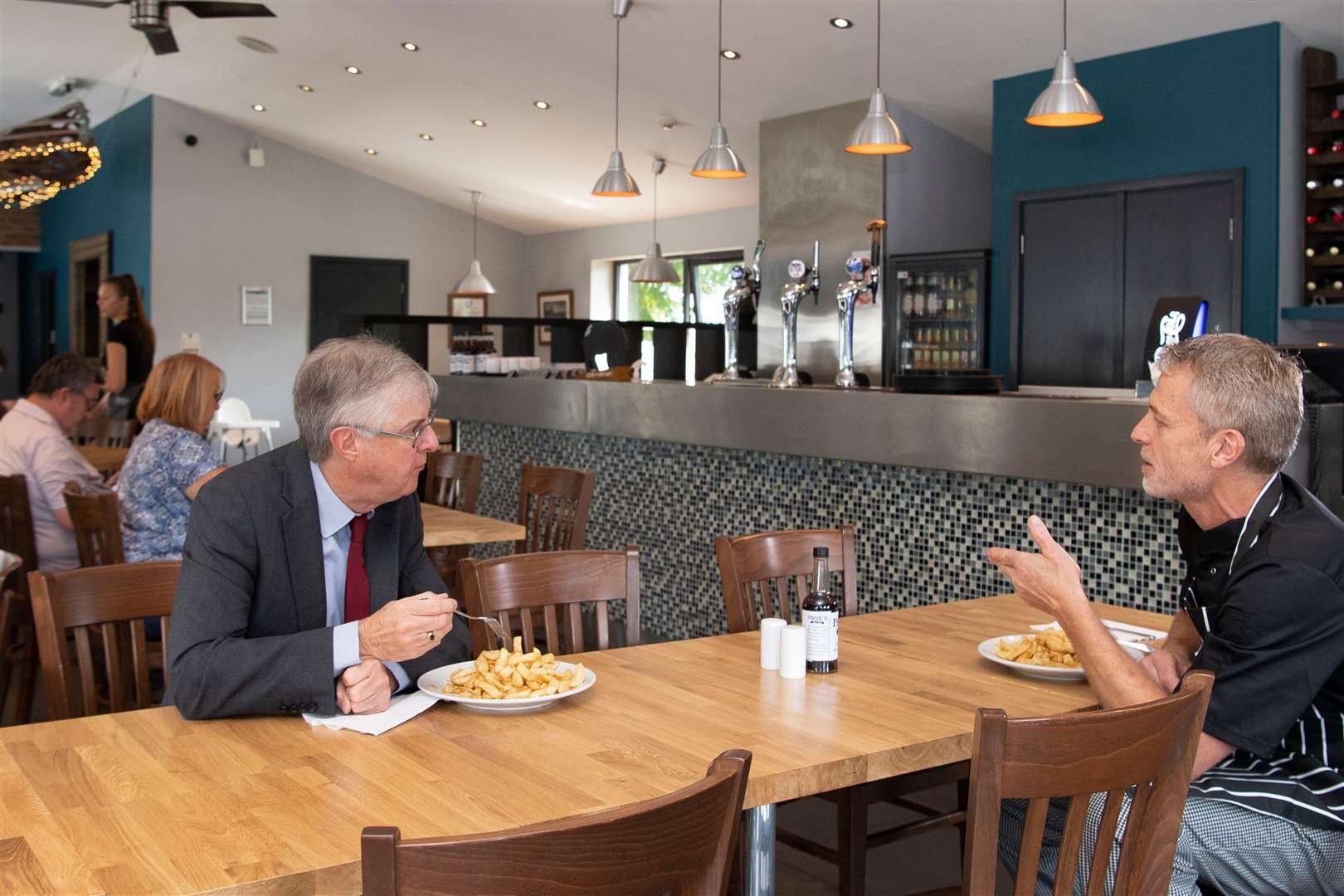 First Minister Mark Drakeford speaks to the owner of Page’s Fish and Chips restaurant, John Page (Matt Horwood/PA)