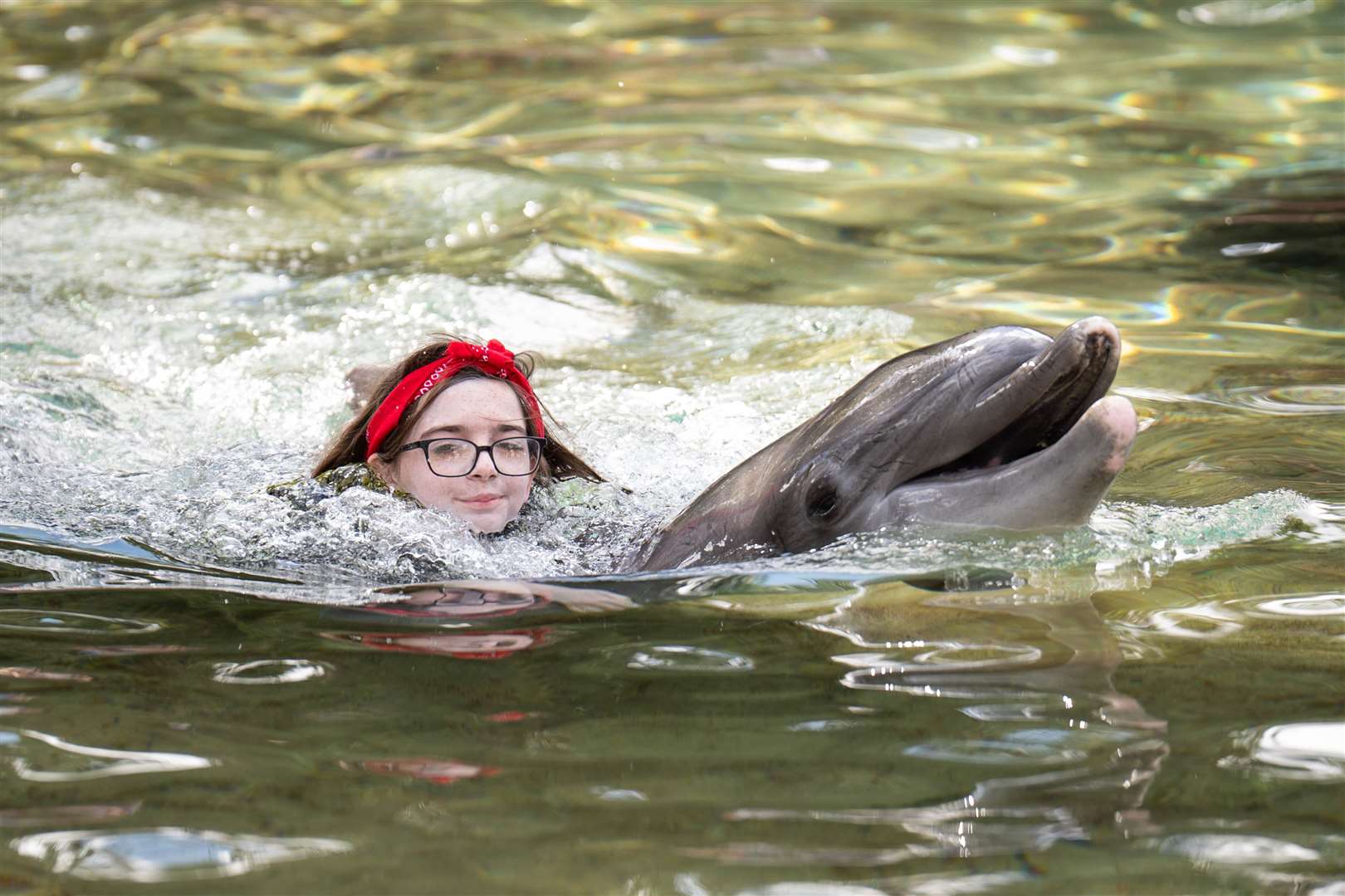 Ayla Dannatt, 12, swims with a dolphin during the Dreamflight visit to Discovery Cove (James Manning/PA)