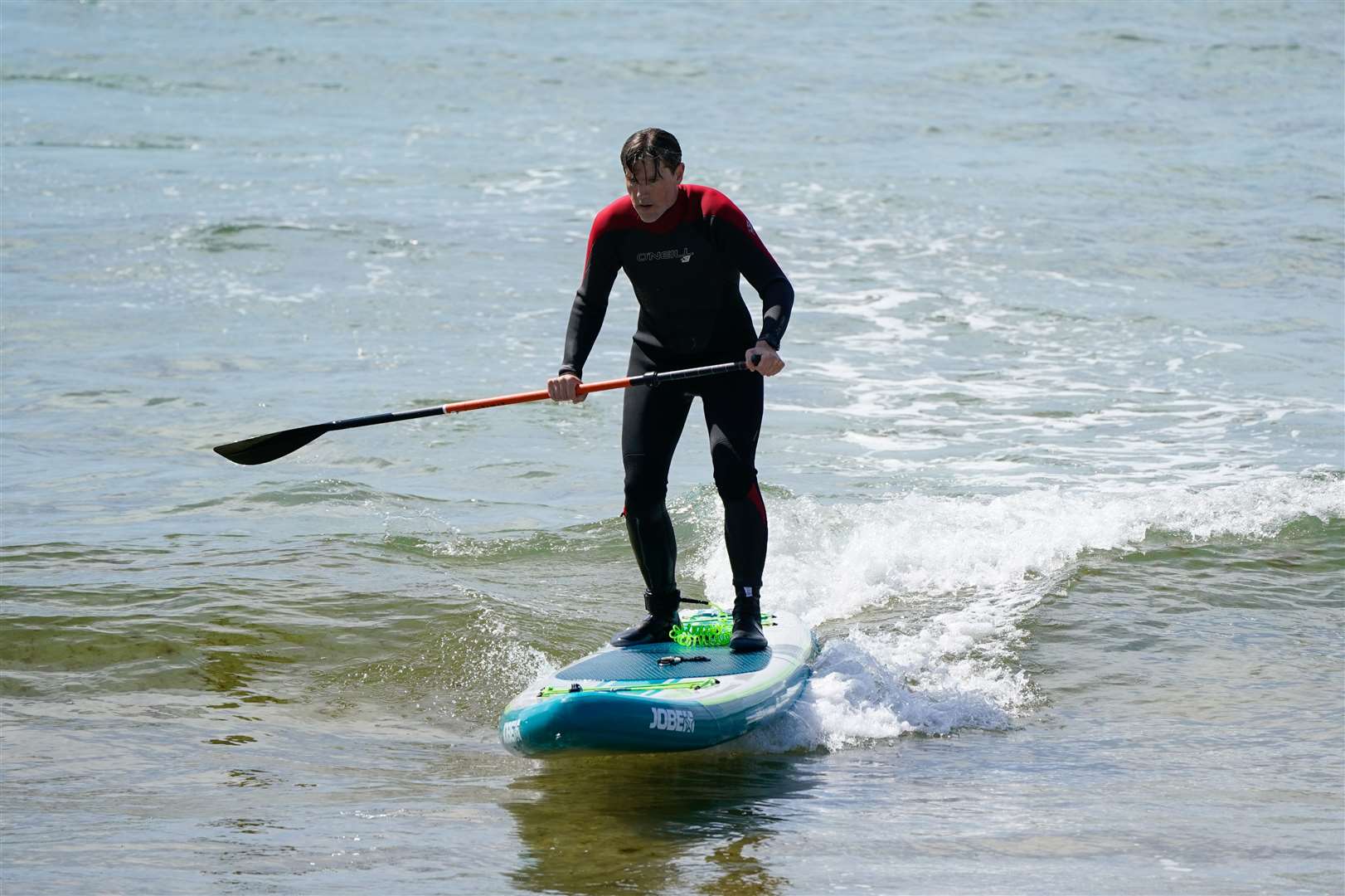 A person paddle boards in the sea off of Bournemouth beach in Dorset (Andrew Matthews/PA)