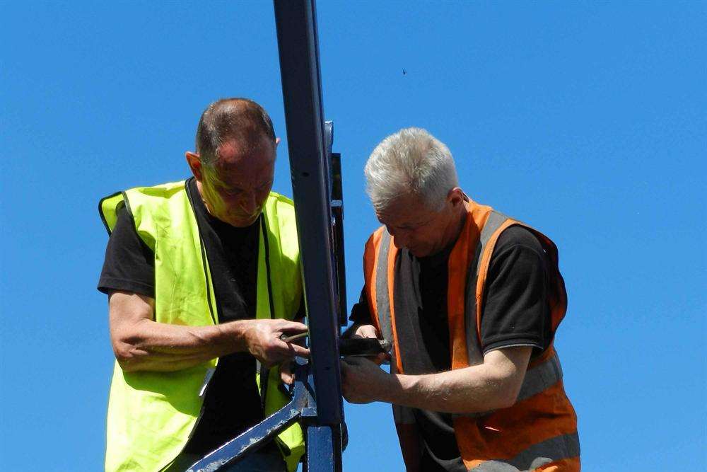 Council workers fixing the repaired archway back into place in July