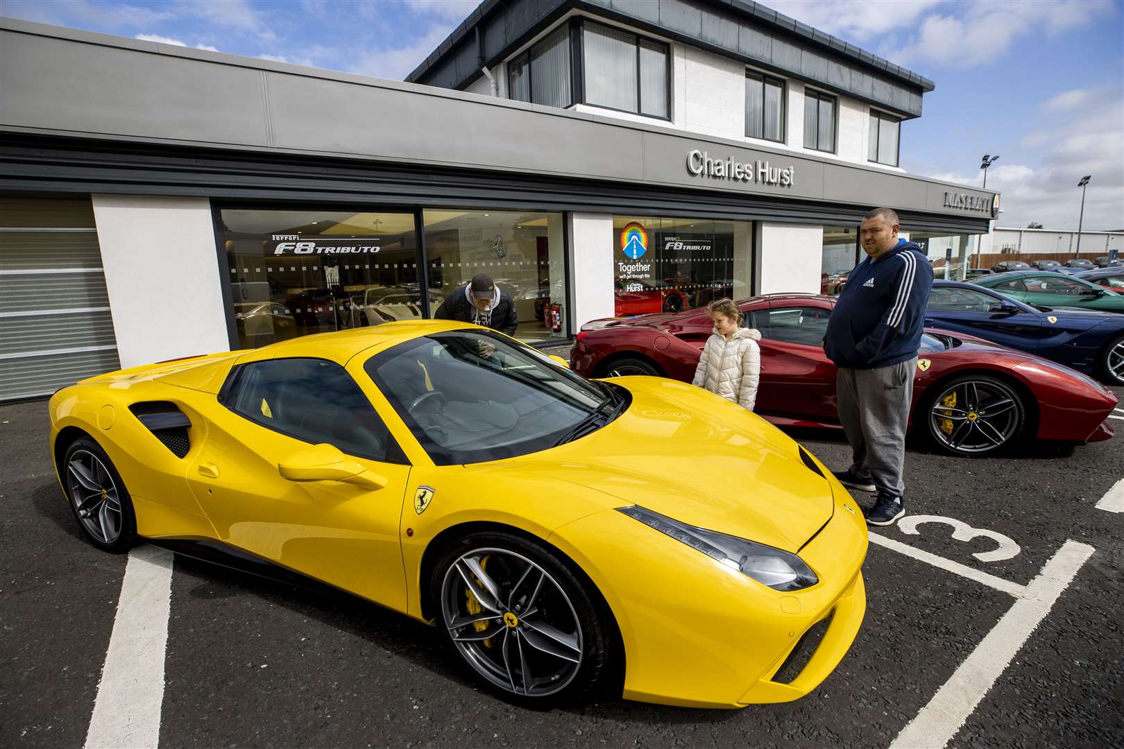 Neil Robinson and his daughter Miley look at Ferrari cars at the Charles Hurst dealership in Belfast (Liam McBurney/PA)