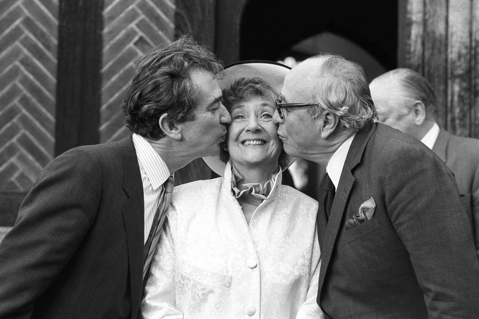 SDP president Shirley Williams receiving a kiss from fellow founding members of the party Bill Rodgers (left) and Lord Jenkins, outside the Church of St Edmunds following her wedding to American professor Richard Neustadt in 1987 (PA)