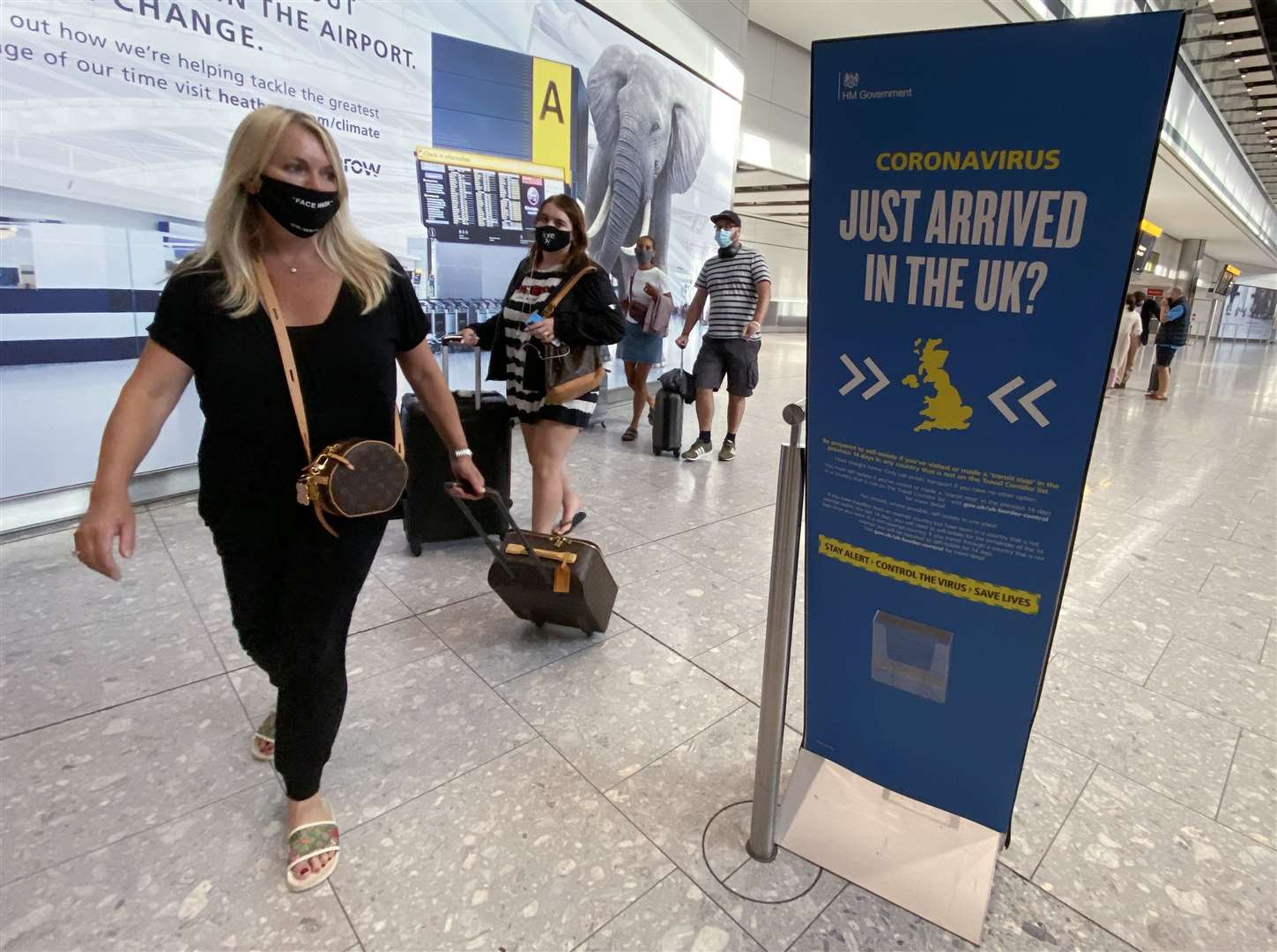 Passengers are reminded of Covid-19 restrictions as they arrive back at Heathrow (Yui Mok/PA)