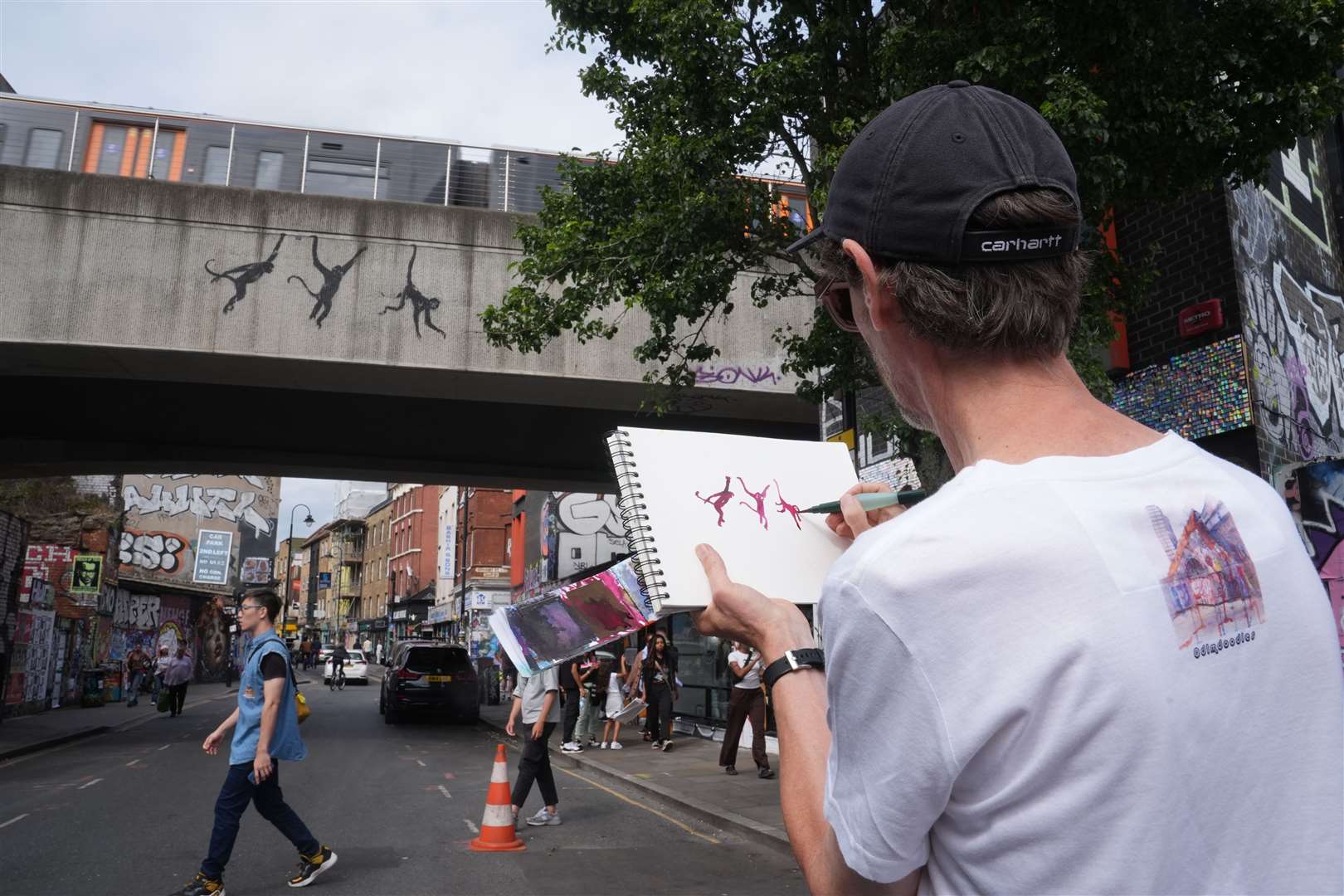 A person draws a new artwork depicting three monkeys unveiled by Banksy (Lucy North/PA)