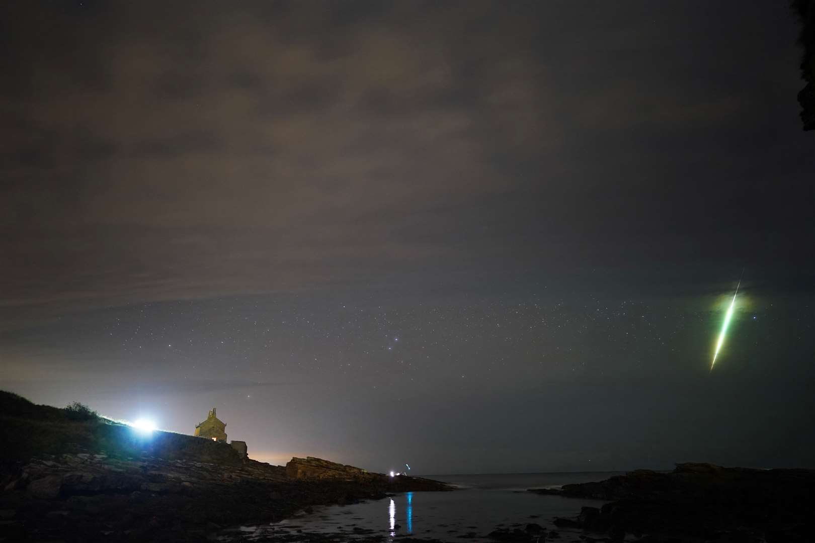 A fisherman watches a meteor during the Draconid meteor shower over Howick rocks in Northumberland (Owen Humphreys/PA)